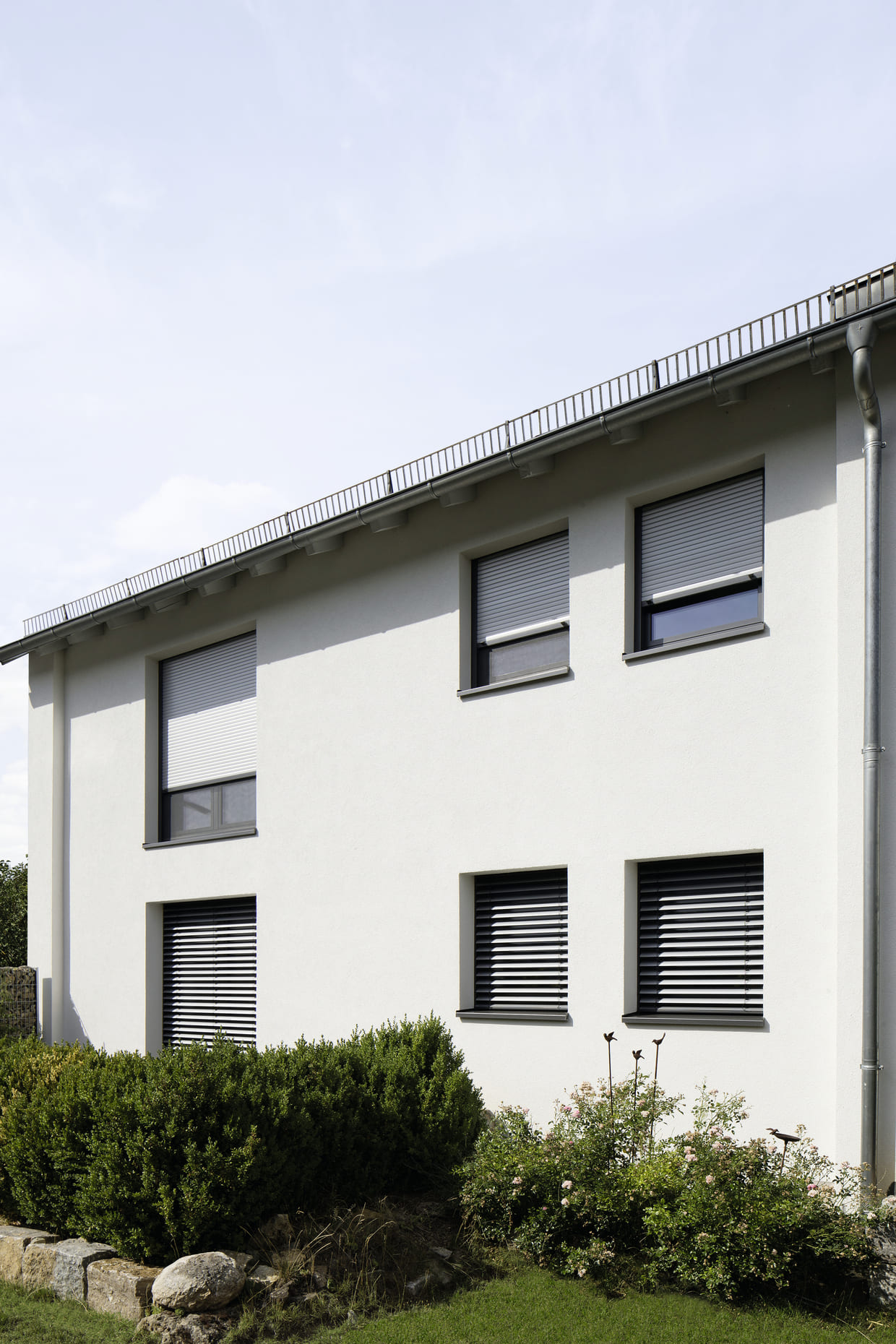 Abb. modernes Mehrfamilienhaus mit mehreren dreiviertel geschlossenen Rollladensystemen von Firma Warema